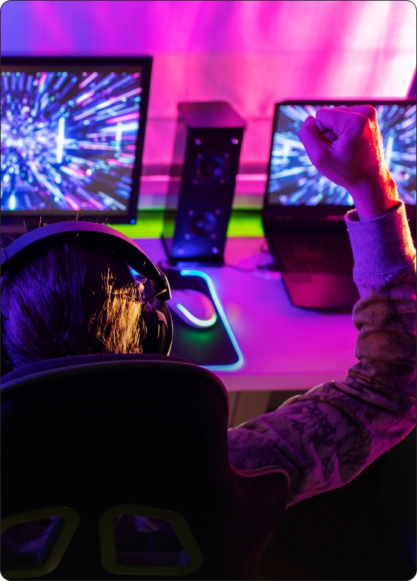 Jogador de esports a celebrar diante de um setup de streaming com luzes roxas